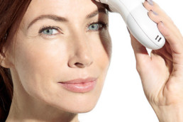 Mature woman using the Nuface device on forehead wrinkles