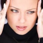 woman rubbing her temples because she has a headache