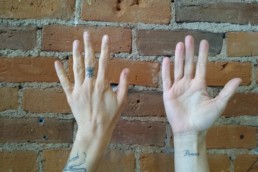 Massage Therapist Hannah's hands against brick wall