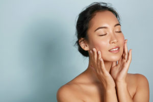 Beautiful woman enjoying the feel of the skin on her face after a facial