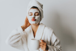 Woman in facial mask with cup of coffee