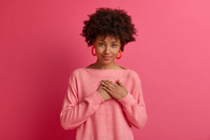 woman in pink sweater being grateful and practicing self care