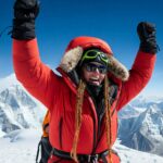 Woman in red winter gear celebrating climbing to the top of Everest