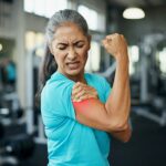 Mature woman in a gym with a sore bicep from working out